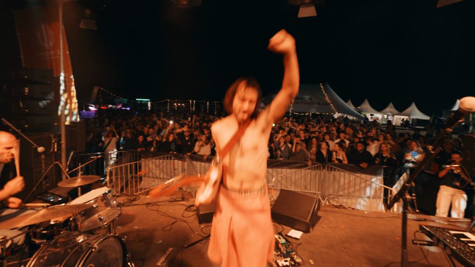 An artist on stage, fist raised to the crowd, Trident Festival 2025